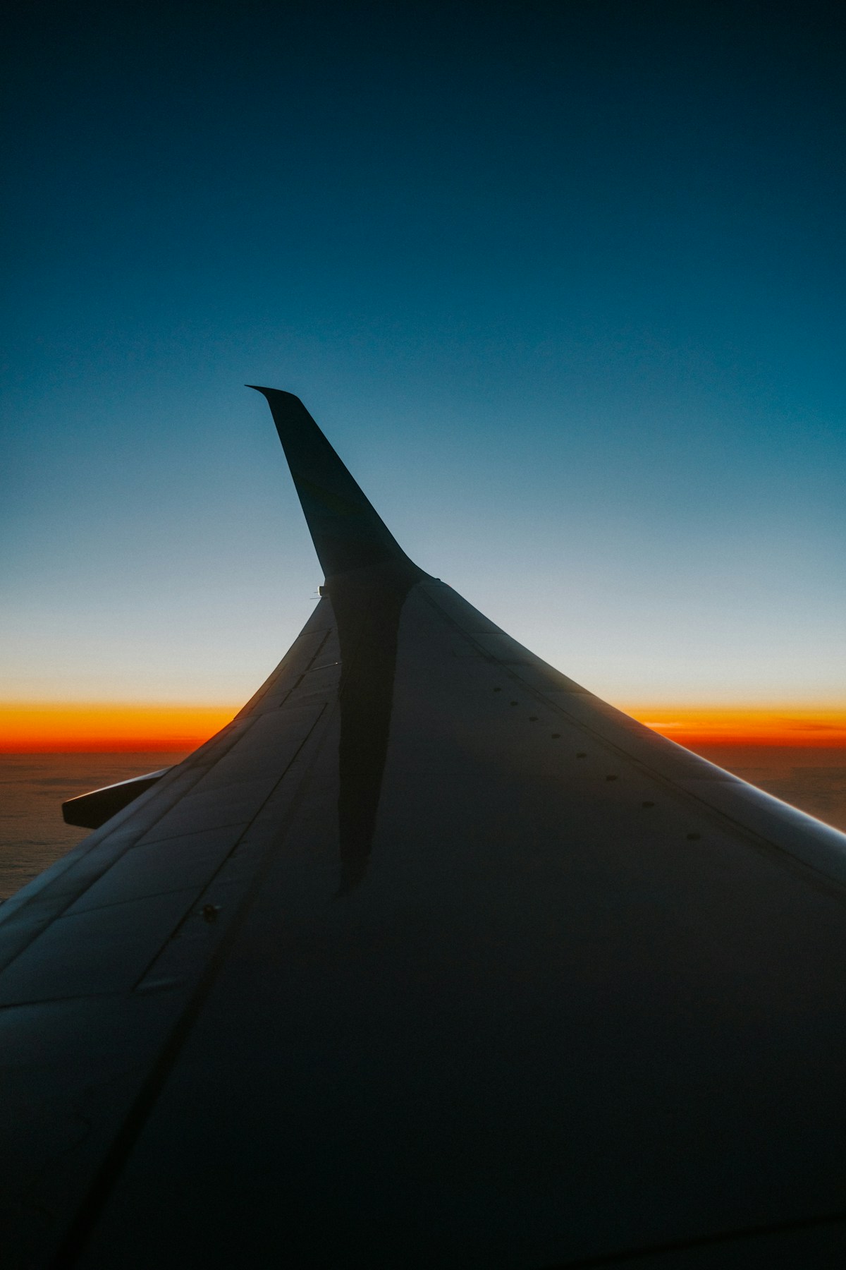 A view of an aircraft wing over sunlit clouds at sunset